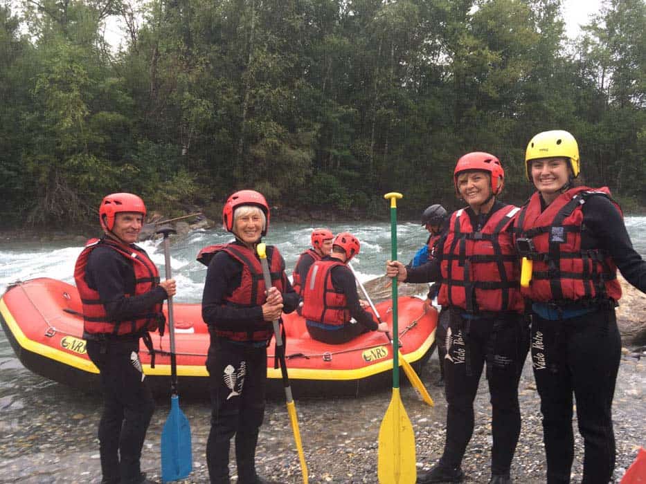 four people standing ready to go white water rafting with boat behind them