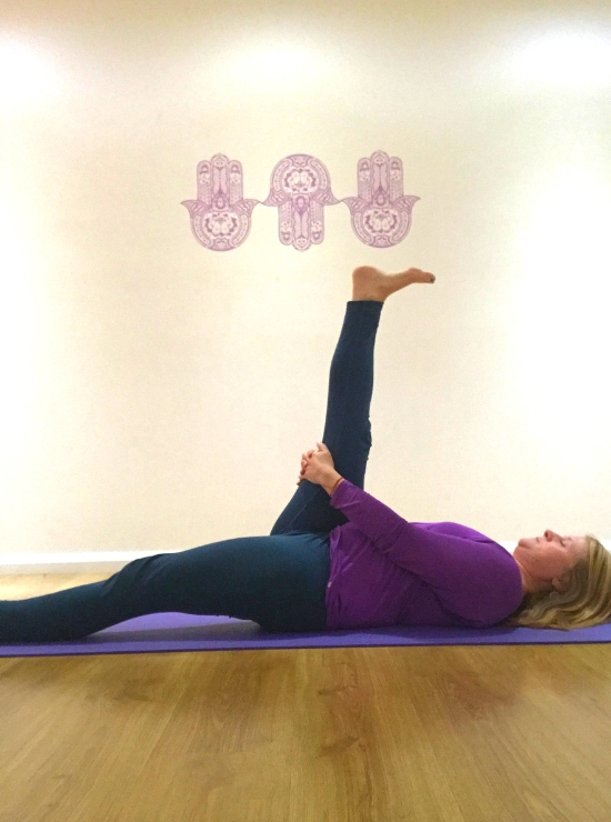 person lying on back foot to sky yin yoga pose ease back pain