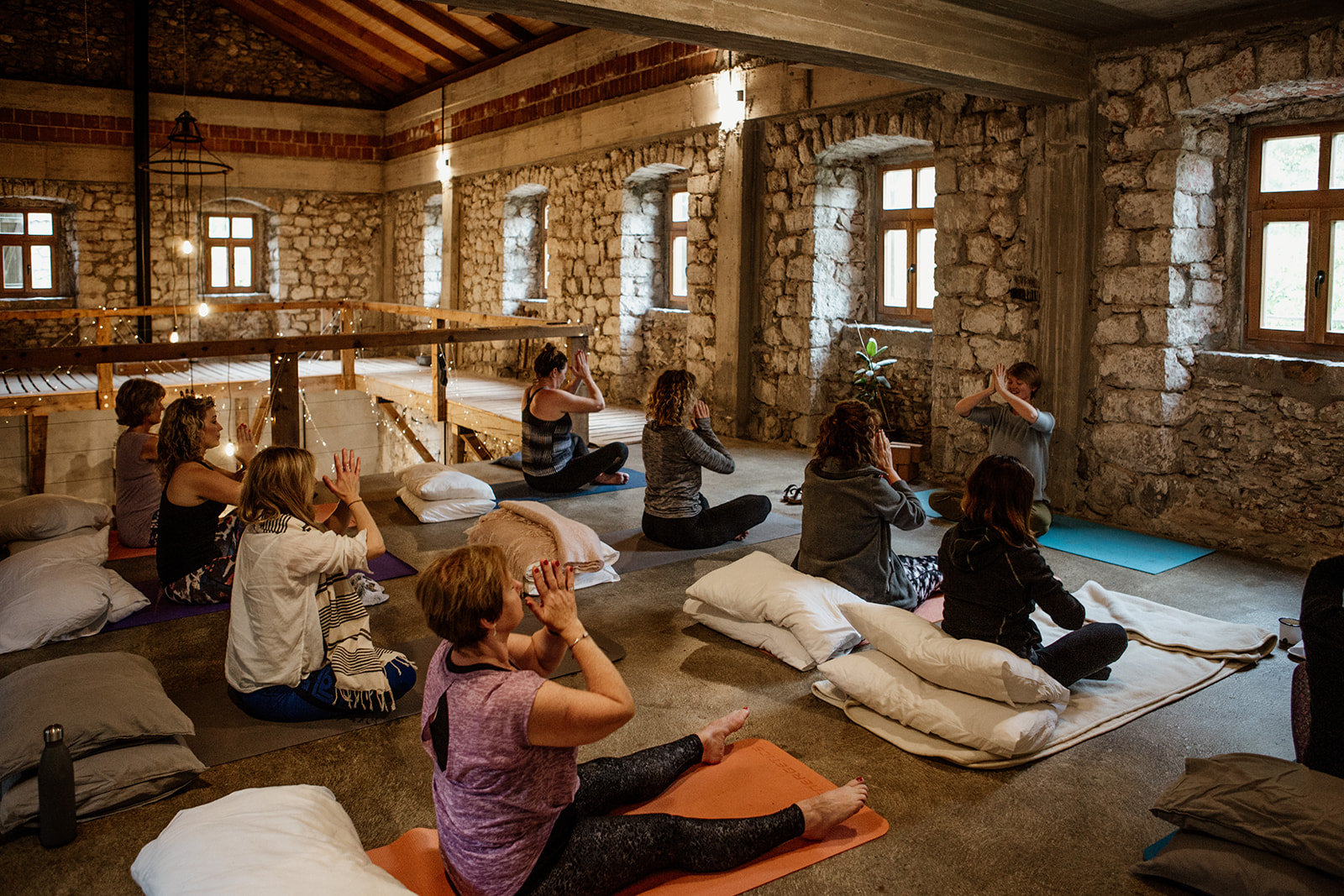 people seated hands in prayer at third eye in yoga space - hiking yoga holiday montenegro