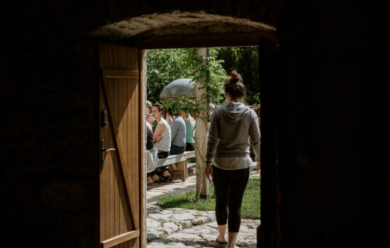 person walking out door to people seated outside - hiking yoga holiday montenegro