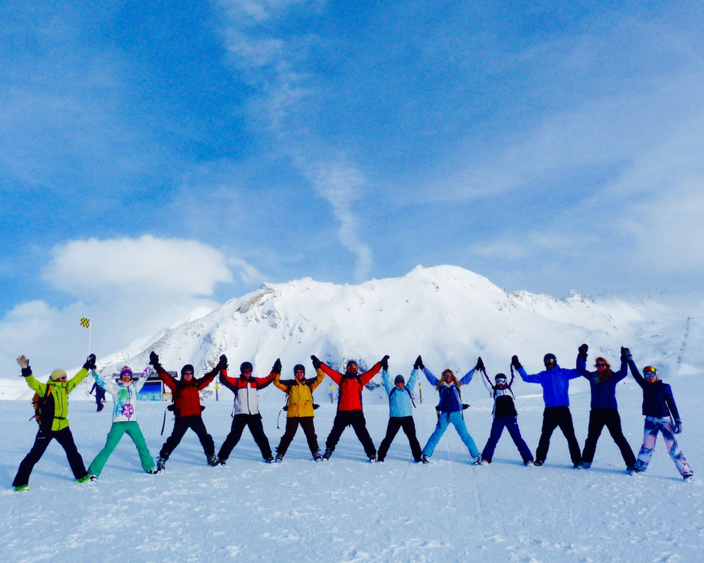 Line of skiers with hands up