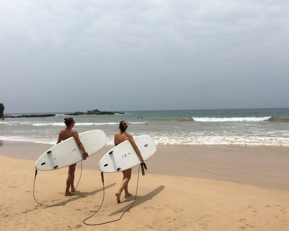 Two surfers carrying boards out to sea