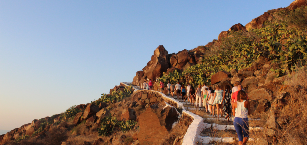guests walking up hillside santorini sunset