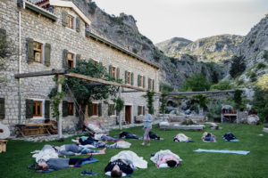 people in savasana outside front of olive mill accommodation - hiking yoga holiday montenegro