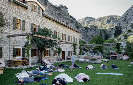 people in savasana outside front of olive mill accommodation - hiking yoga holiday montenegro