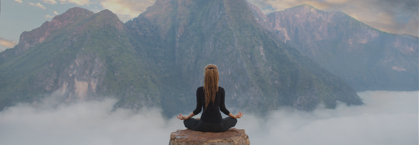 woman on rock above clouds in mountains