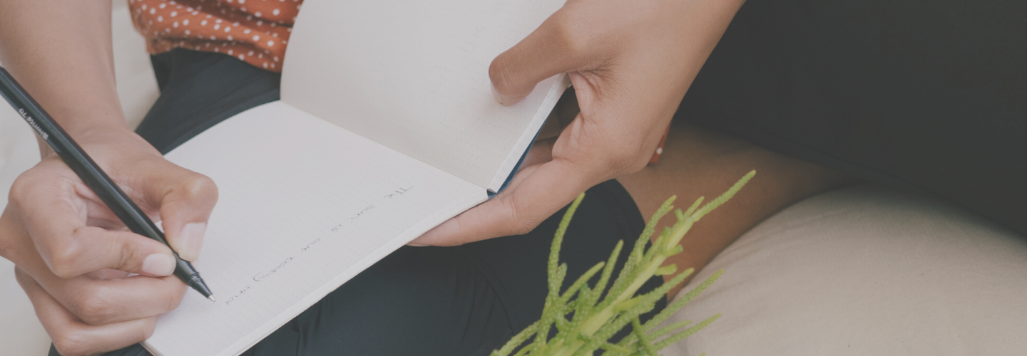 womans hands writing in notebook