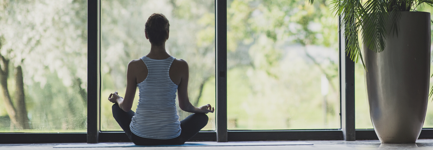 woman sat meditation pose looking out window