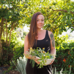 Woman holding edible flowers in bowl by tree