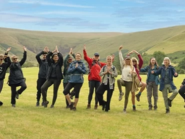 people doing yoga pose outside with brecon beacons behind them