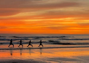 people doing yoga on the beach at sunset